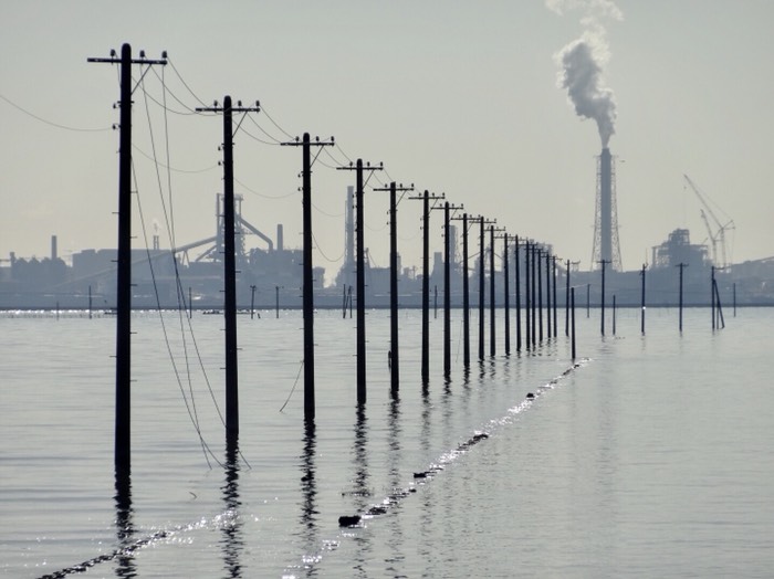 海に立つ電柱と工業地帯